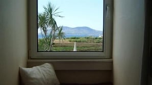 Una habitación con ventana que da a un paisaje, un banco acolchado y un almohadón.