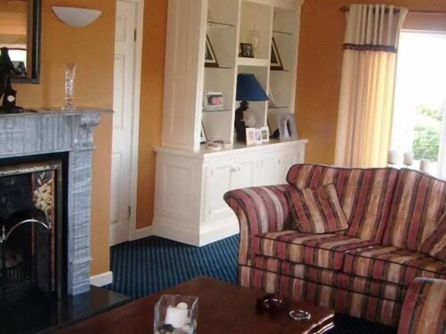 Una sala de estar con chimenea, un sofá a rayas, un armario blanco y una alfombra azul.