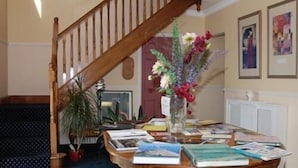 Una escalera de madera con un jarrón de flores sobre una mesa llena de libros.