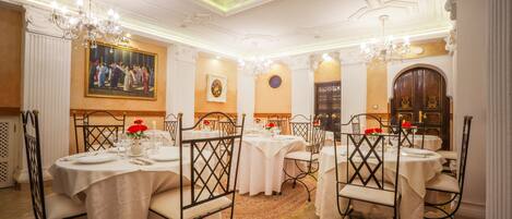 Une salle à manger élégante, agrémentée de lustres somptueux, de nappes blanches et de chaises classiques.