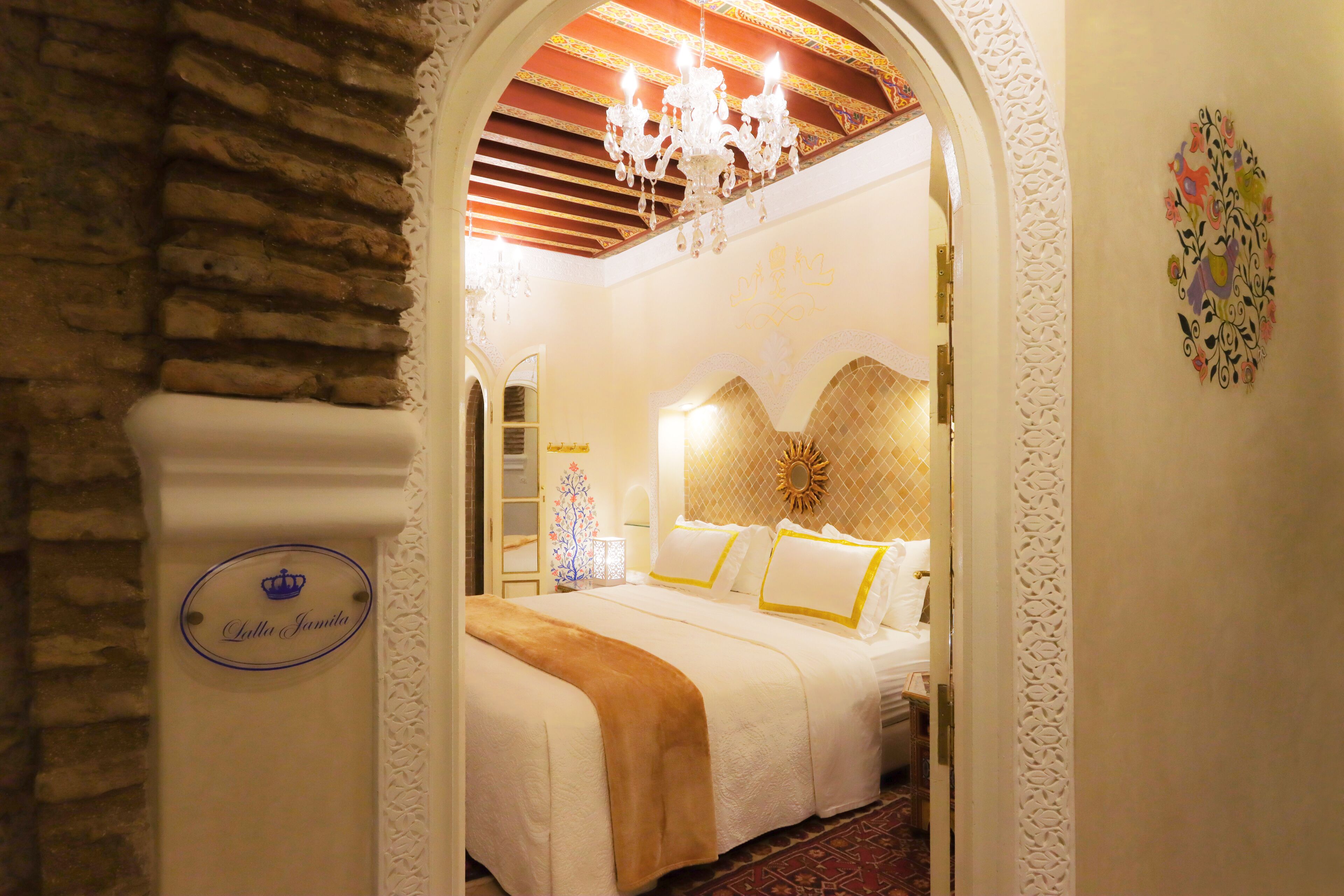Habitación de hotel con una cama, una araña y un adorno mural.