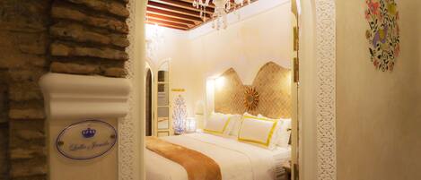 A hotel room with a bed, a chandelier, and a decorative wall piece.