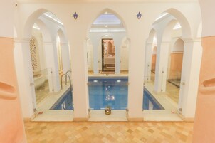Una piscina con paseos en arco y suelo de baldosas.