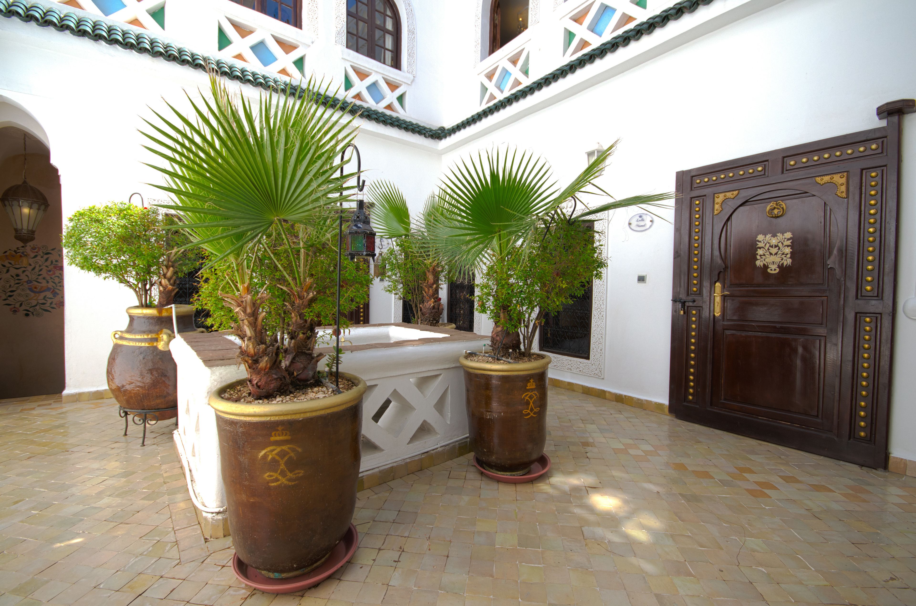 A courtyard with potted plants, a decorative door, and a tiled floor.