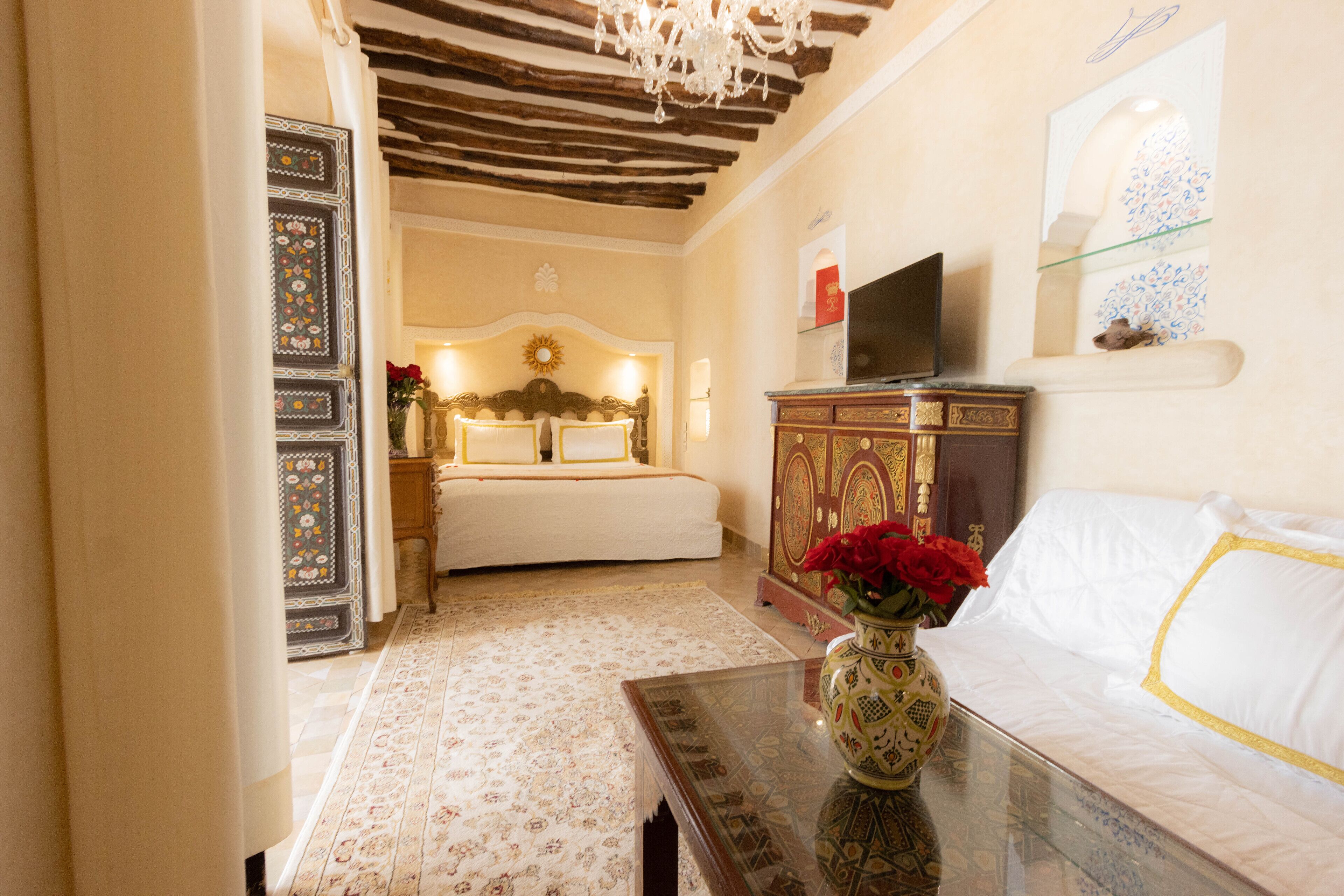 A bedroom with a bed, a TV, a cabinet, and a vase with flowers.