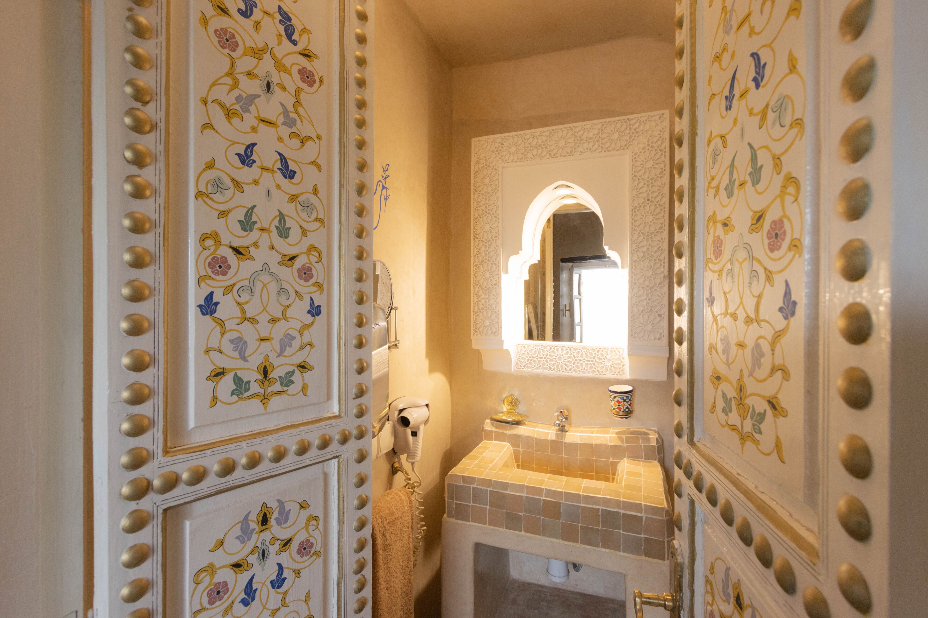 Une salle de bain avec des décorations murales élaborées, un lavabo et un miroir.