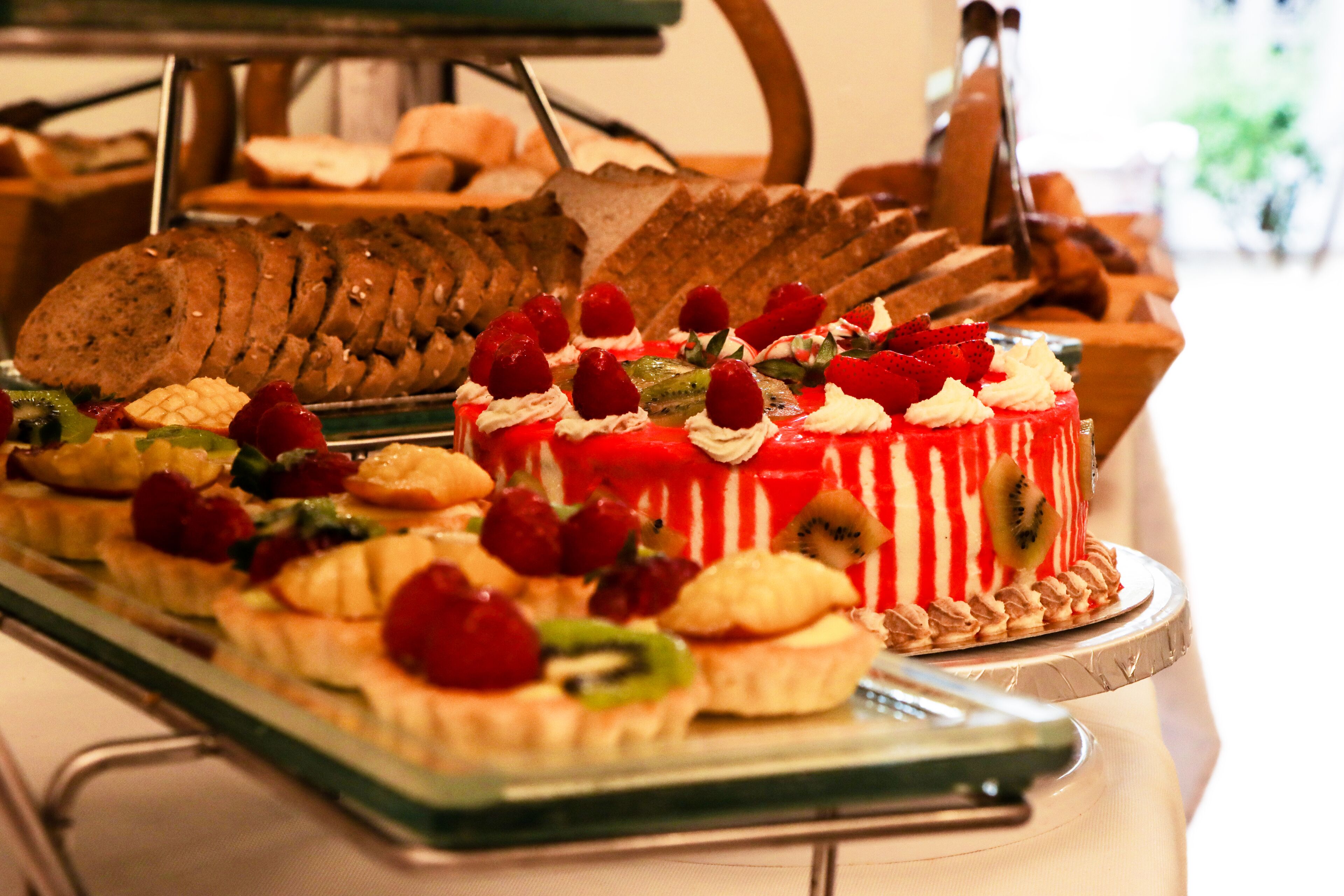 A variety of desserts on a buffet table, including cakes and pastries with fruit toppings.