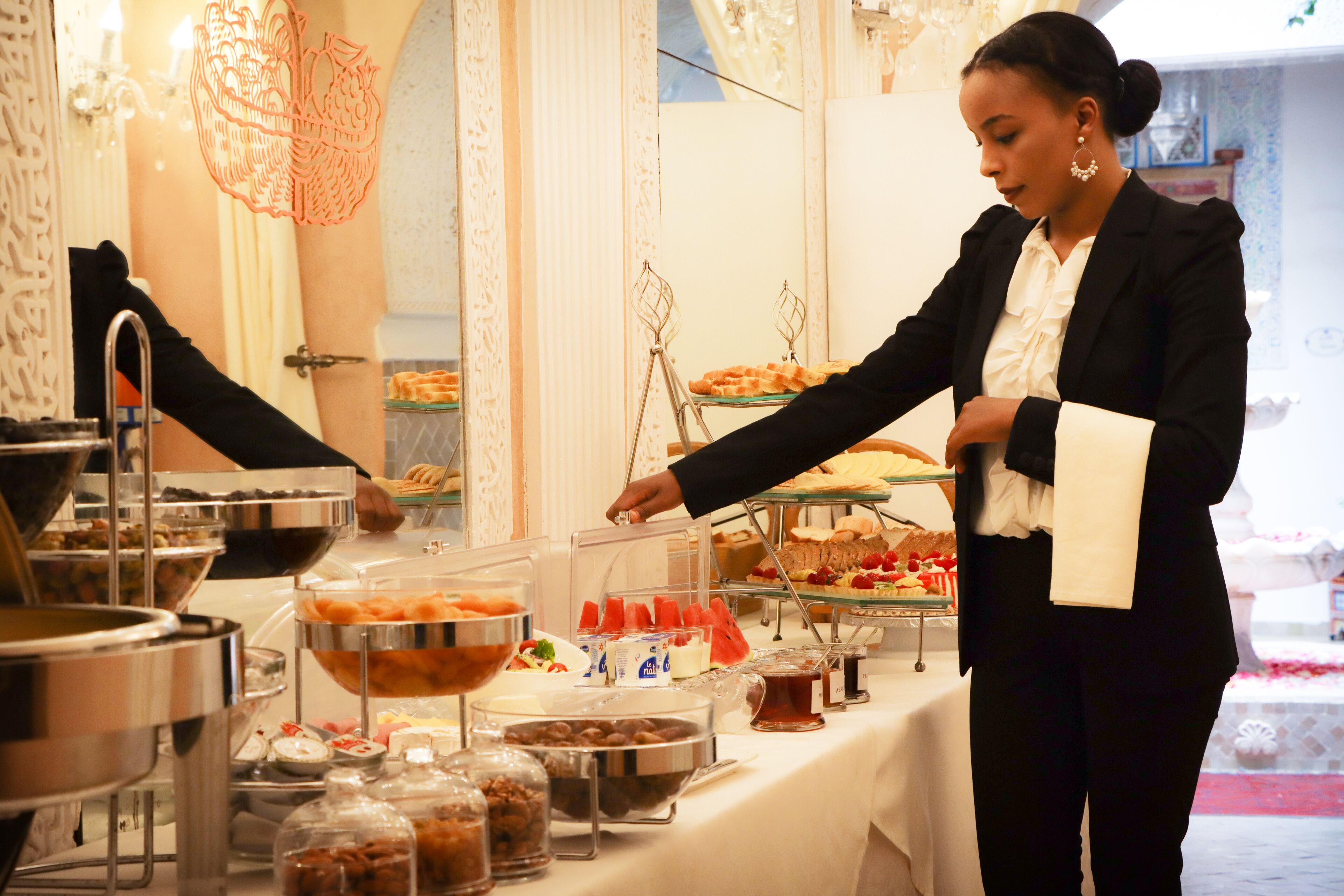 A buffet setup with various food items and a person serving.