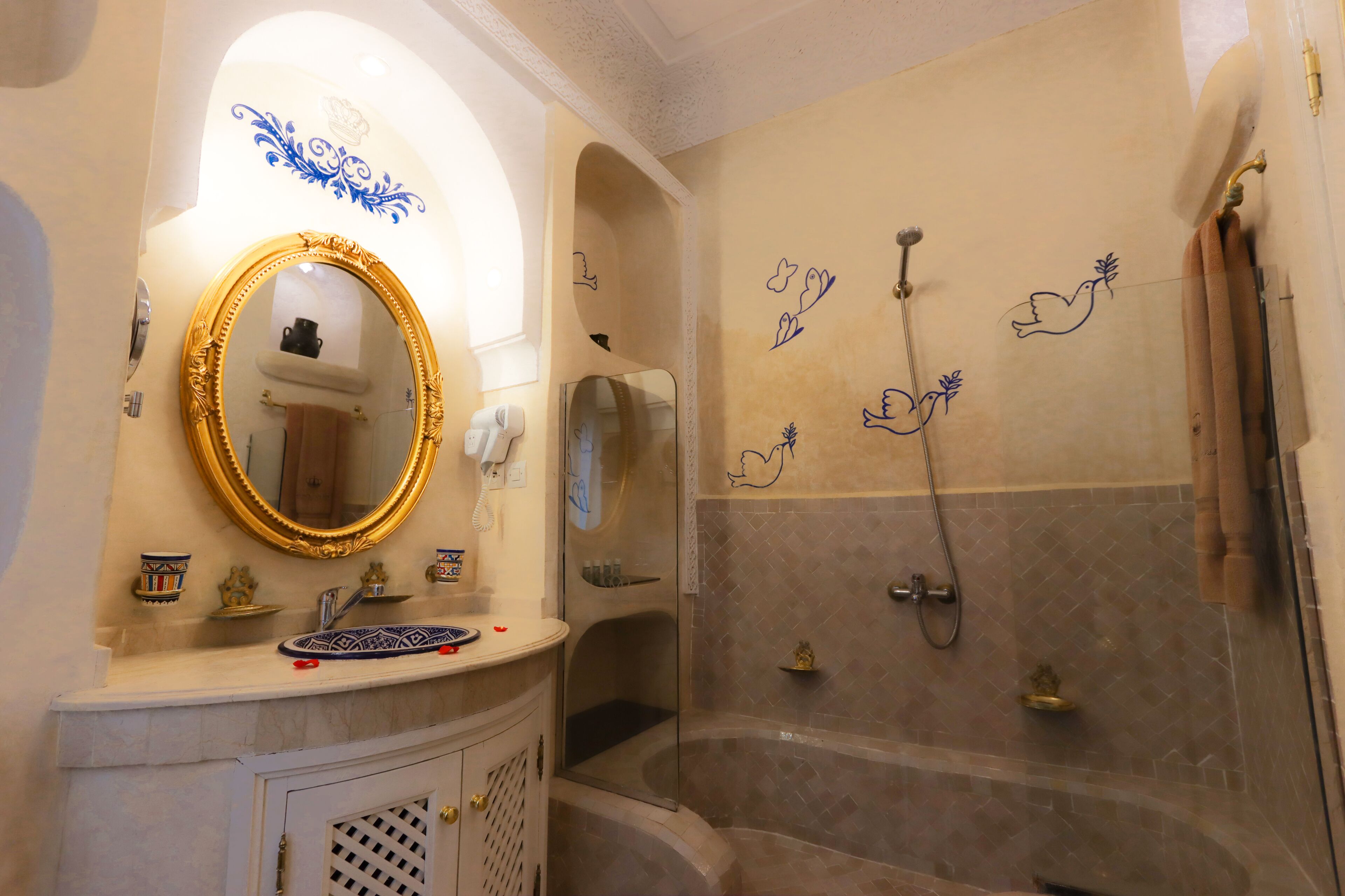 Une salle de bain dotée d’un grand miroir, d’une baignoire et d’œuvres d’art décoratives sur les murs.