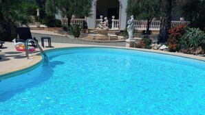 Una piscina azul cristalina con una estatua y un flotador con forma de cisne.