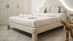 Un dormitorio con cama de madera, ropa de cama blanca y cabecera con luces empotradas.