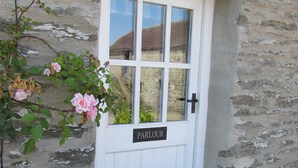 Una puerta blanca con un letrero que dice "PARLOUR" y una ventana que refleja un paisaje rural.