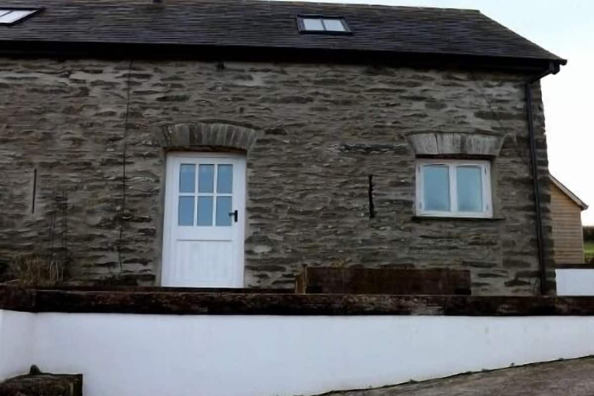 Un edificio de piedra con una puerta blanca y dos ventanas.