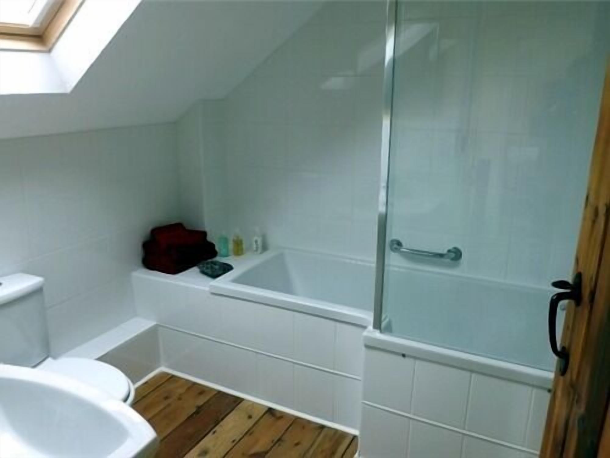 Ein Badezimmer mit Dachfenster, einer Badewanne, einer Toilette und einer Duschkabine.