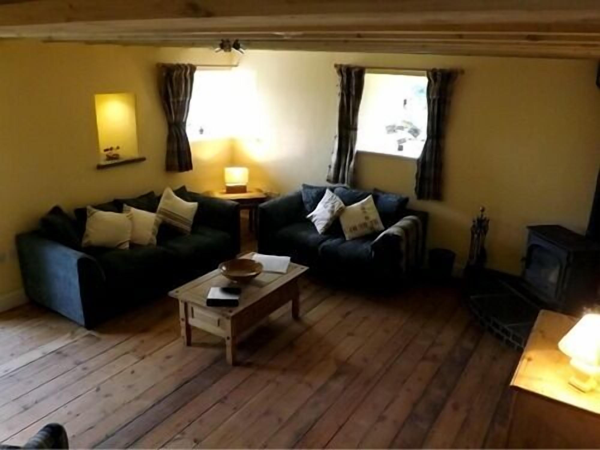 A cozy living room with two dark sofas, a wooden coffee table, and a fireplace.