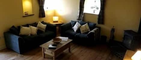 Una sala de estar acogedora con dos sofás oscuros, una mesa de centro de madera y una chimenea.