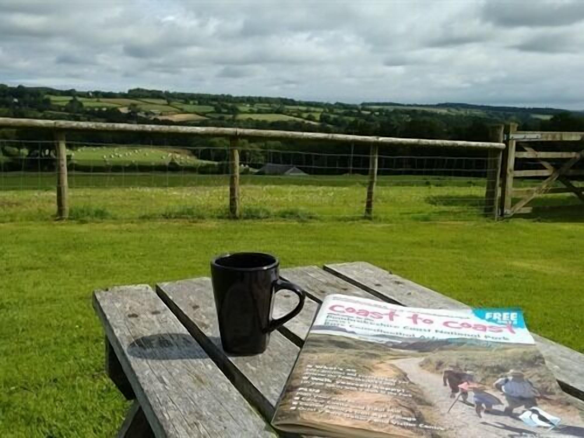 Ein Picknicktisch mit einer schwarzen Tasse und einer Broschüre mit dem Titel 'Coast to Coast'.