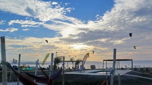 A beach with hammocks and flags, a clear sky, and kites flying. - Bamboo Paracas Resort (Paracas)