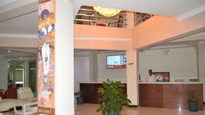 A hotel lobby with a reception desk, a large screen, and a 'Welcome!' sign.