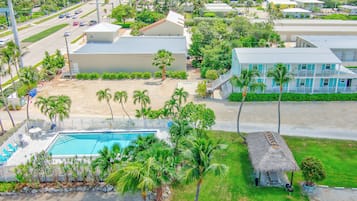Luchtbeeld van een resort met een zwembad, palmbomen en strandwoningen.
