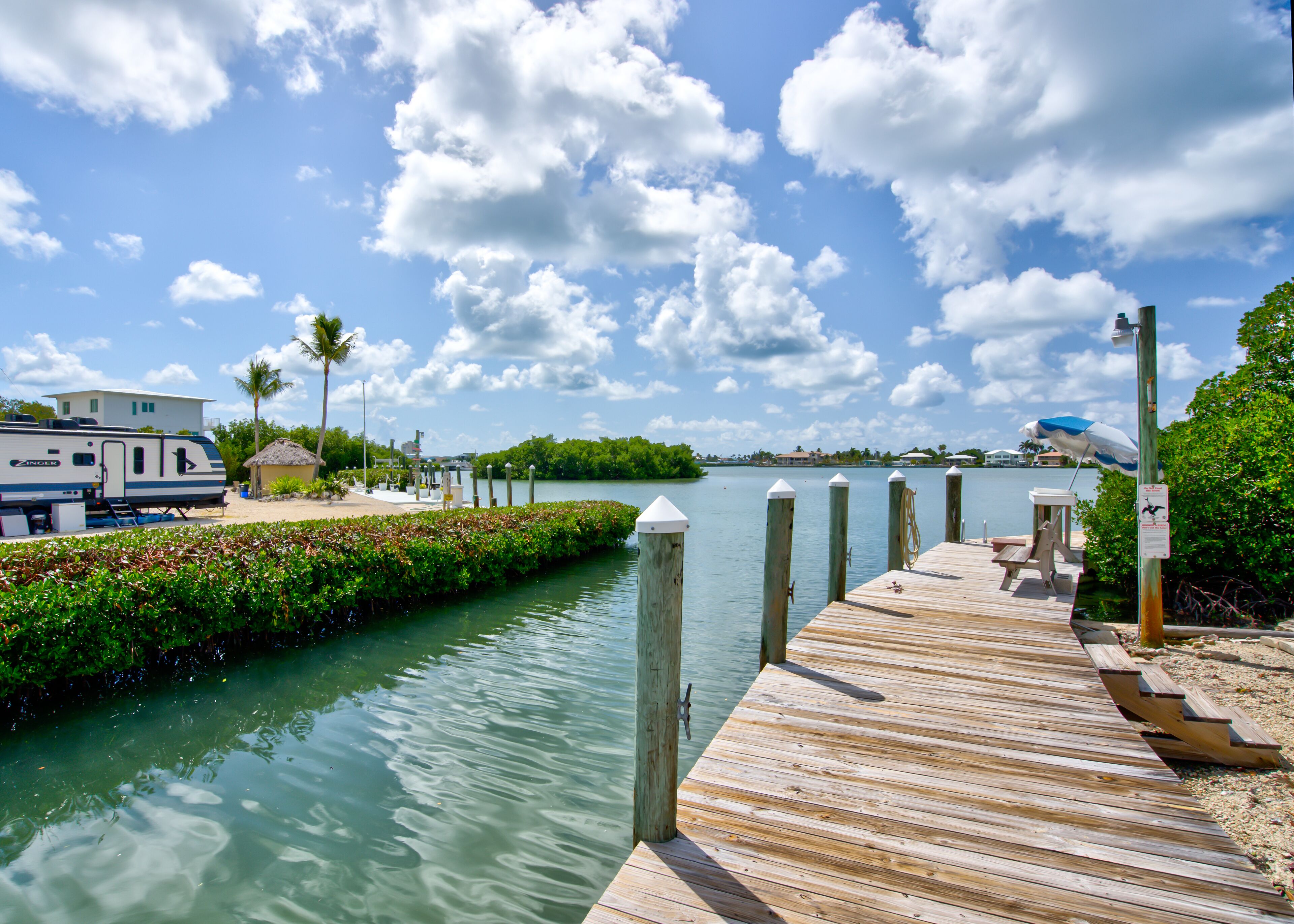 A wooden dock extending into a calm body of water, with a clear sky and a few clouds above.