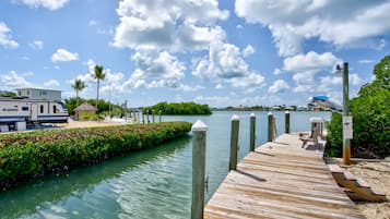 A wooden dock extending into a calm body of water, with a clear sky and a few clouds above.