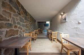 Ein Restaurant mit Steinwänden, Holztischen und -stühlen sowie einem an der Wand montierten Fernseher.