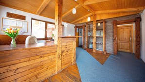 A wooden reception area with a reception desk, a vase of flowers, and a wall with a bulletin board.