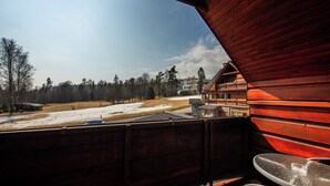 A wooden cabin with a balcony overlooking a snowy landscape and a clear sky.