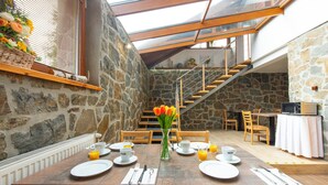 A dining area with a stone wall, wooden furniture, and a staircase.