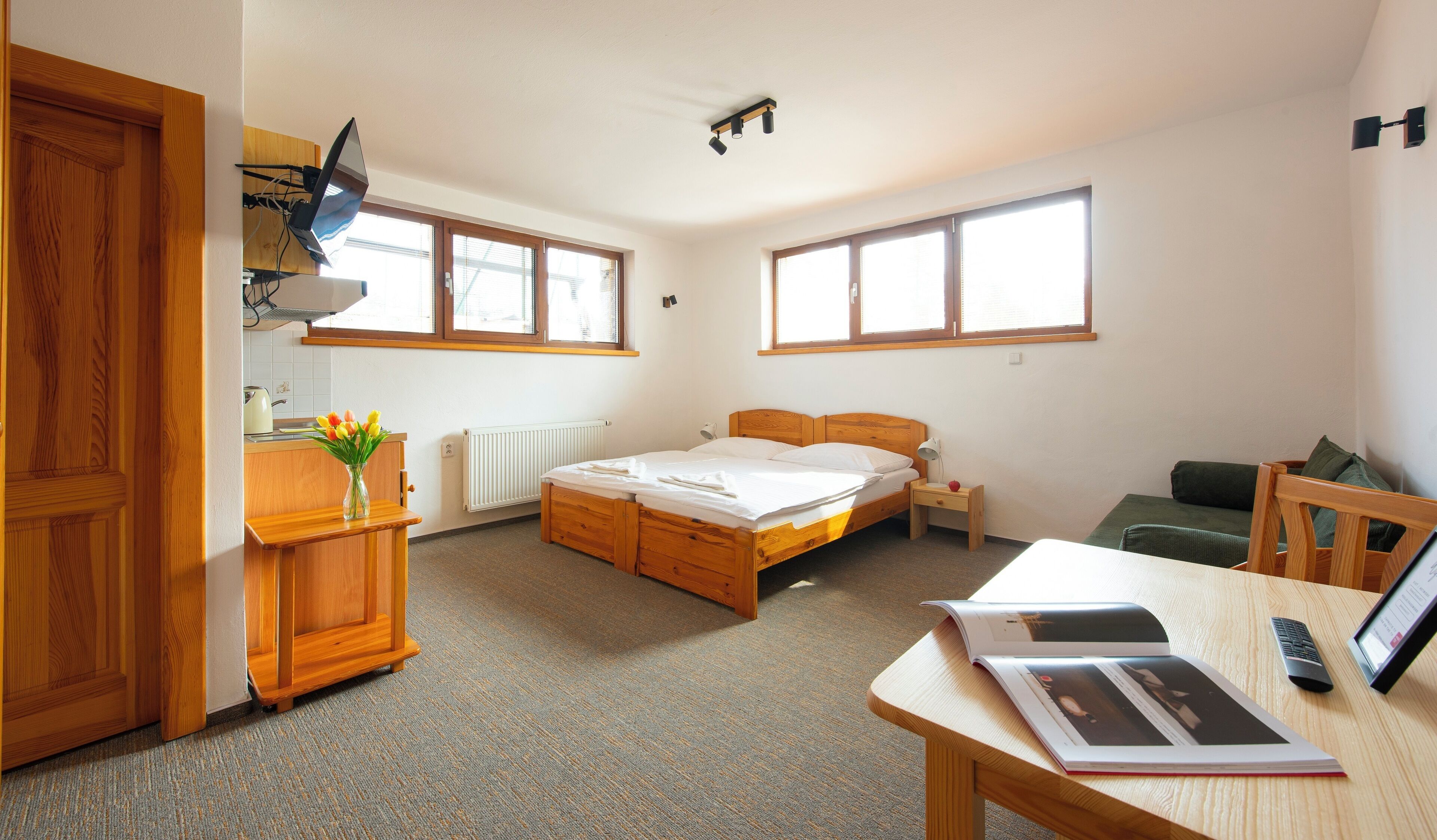 A bedroom with a wooden bed, a desk with a lamp, a chair, and a window.