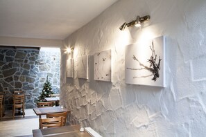 Enjoy casual dining in a warm and inviting space with a rustic backdrop, framed artworks, and comfortable seating.