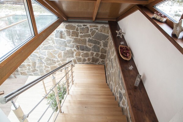 Staircase with a stone accent wall and a shelf with decorative items.