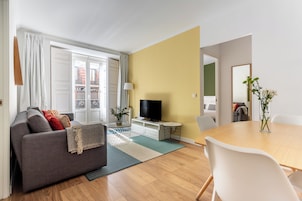 Ein modernes Wohnzimmer mit grauem Sofa, einem Holzesstisch und einem Fernseher.