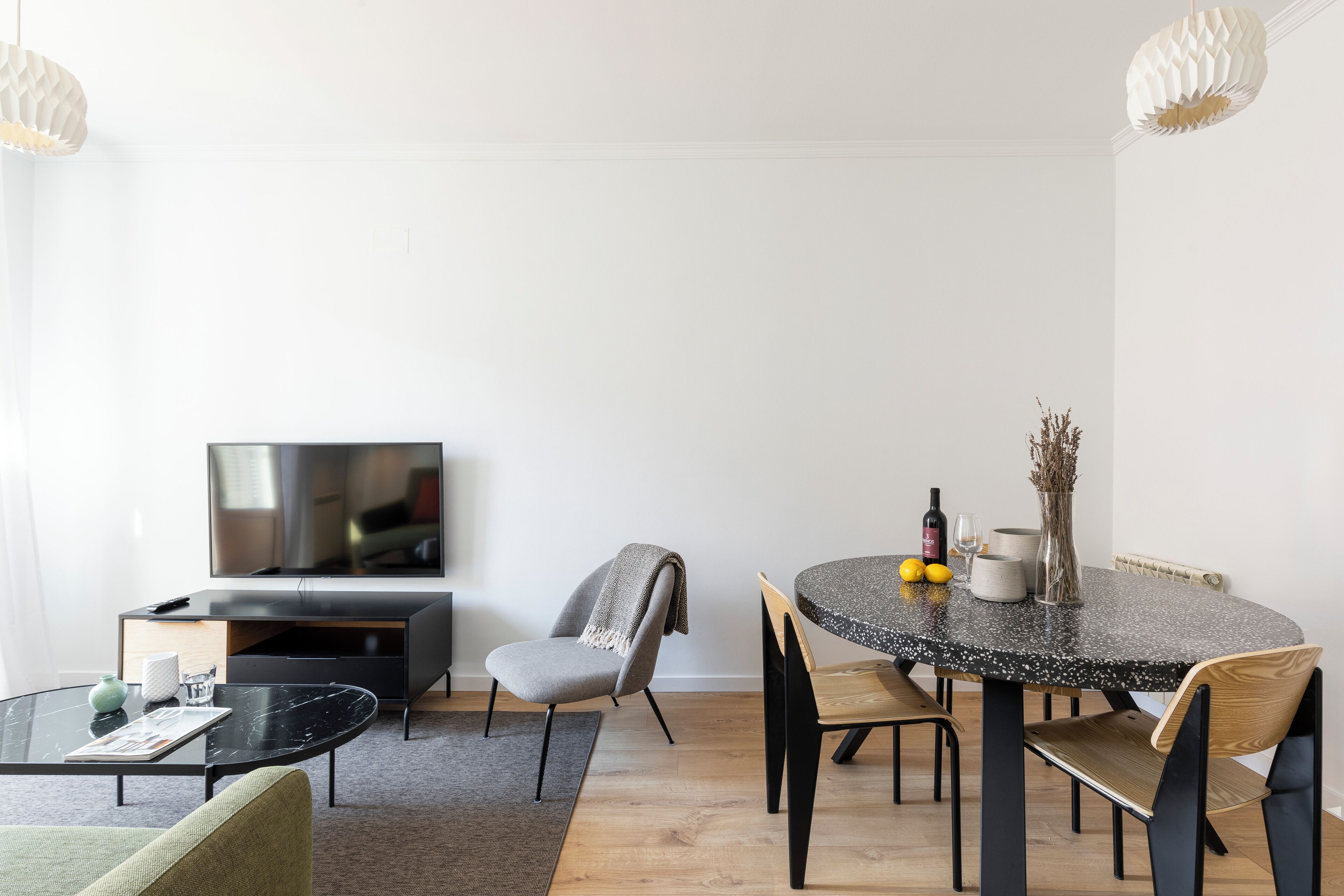 A modern living room with a TV, seating, a dining table, and a fireplace.