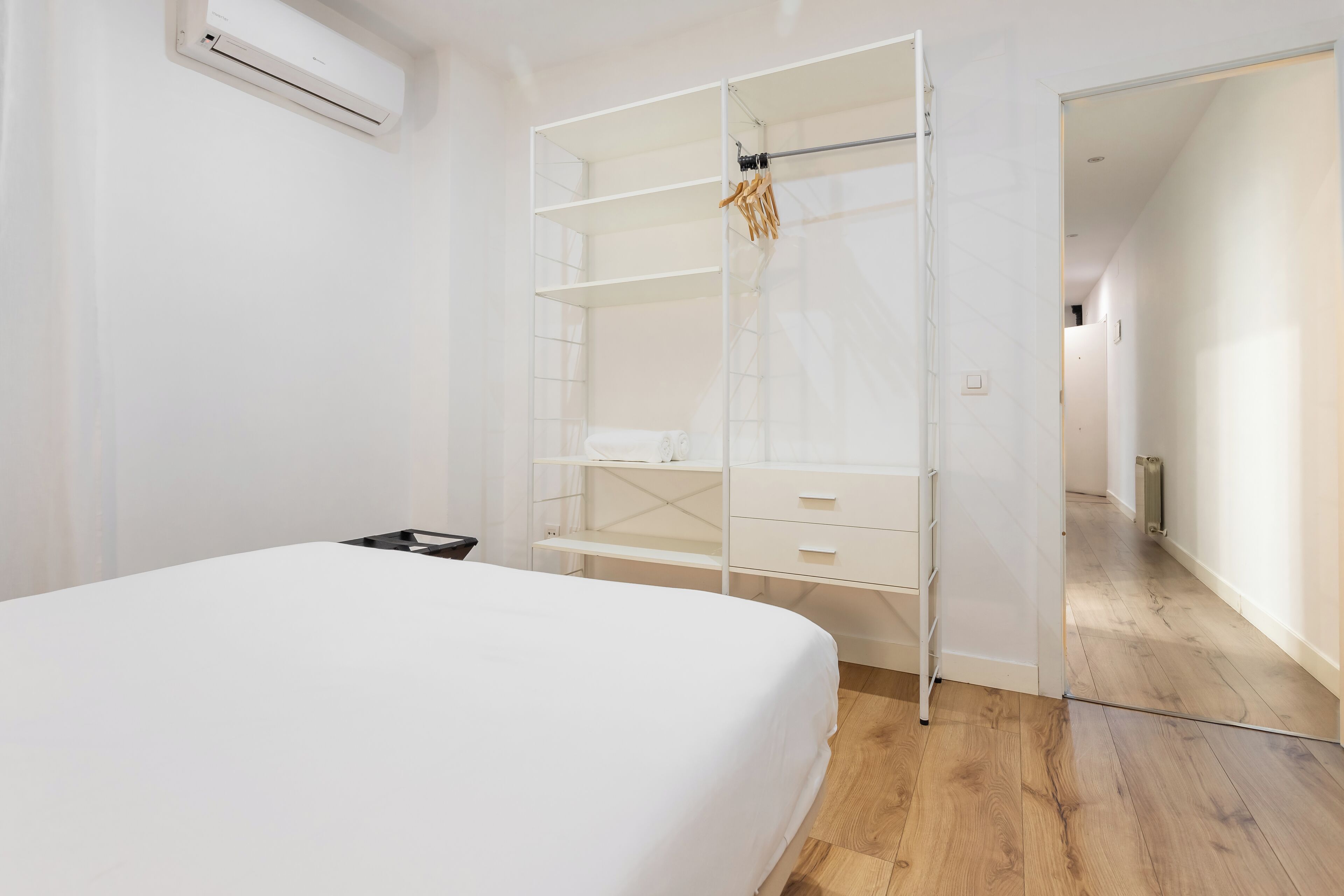 Quarto com uma cama, um guarda-roupa branco e chão de madeira.