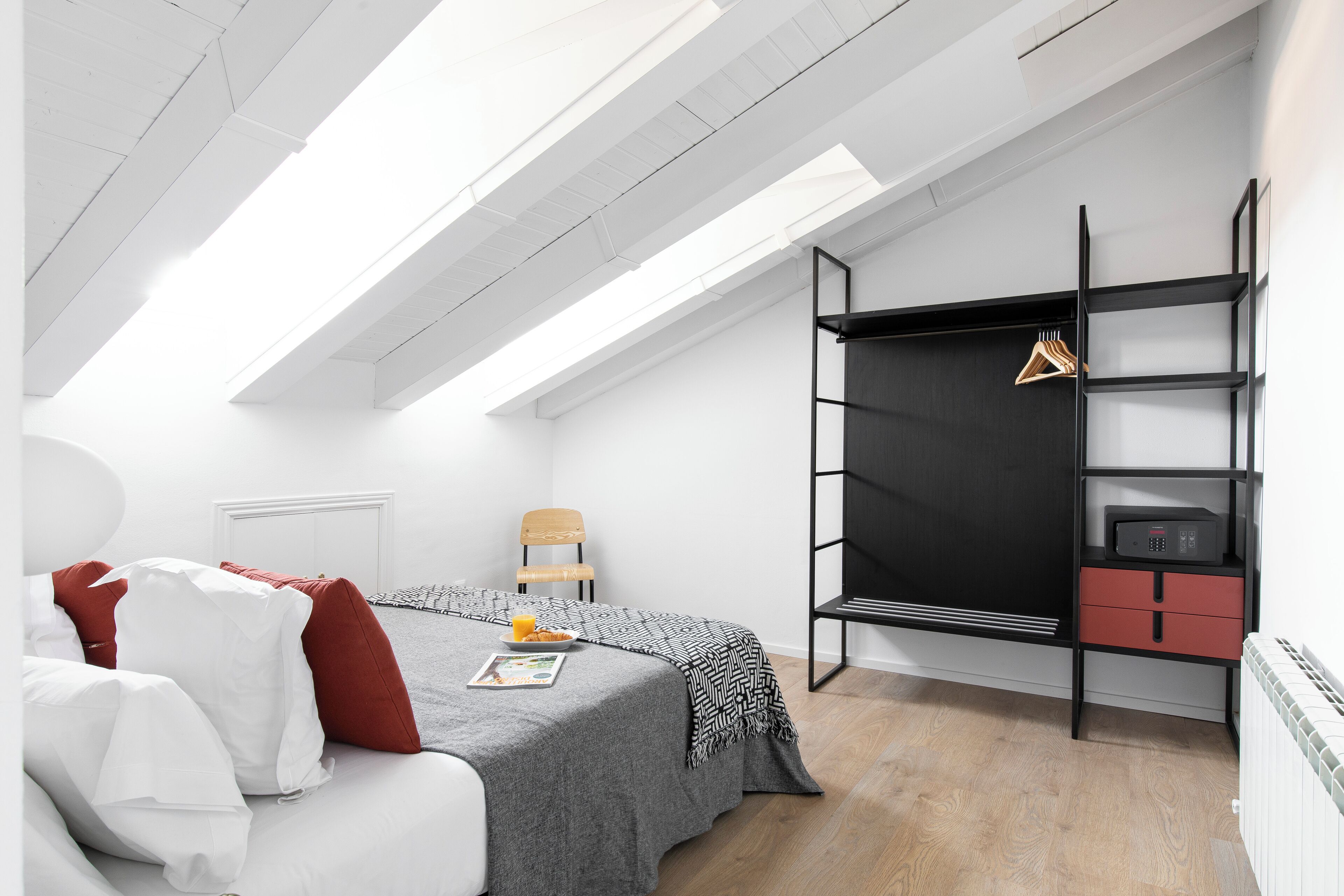 Un dormitorio con una cama, una silla, un escritorio y estanterías.