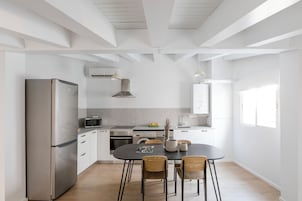 Eine moderne Küche mit Edelstahl-Kühlschrank, Mikrowelle und Backofen, Holzstühlen und einem Esstisch.