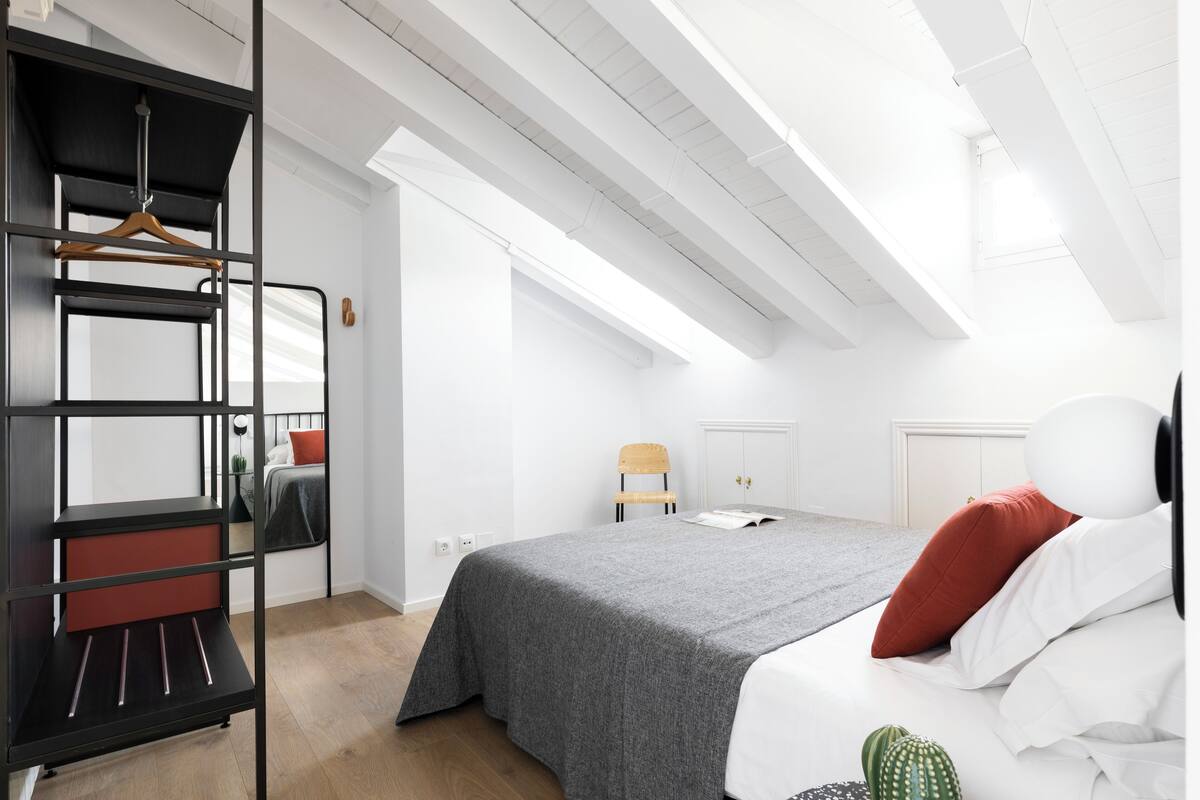 Een moderne slaapkamer met een bed, een kledingkast en een bureau.