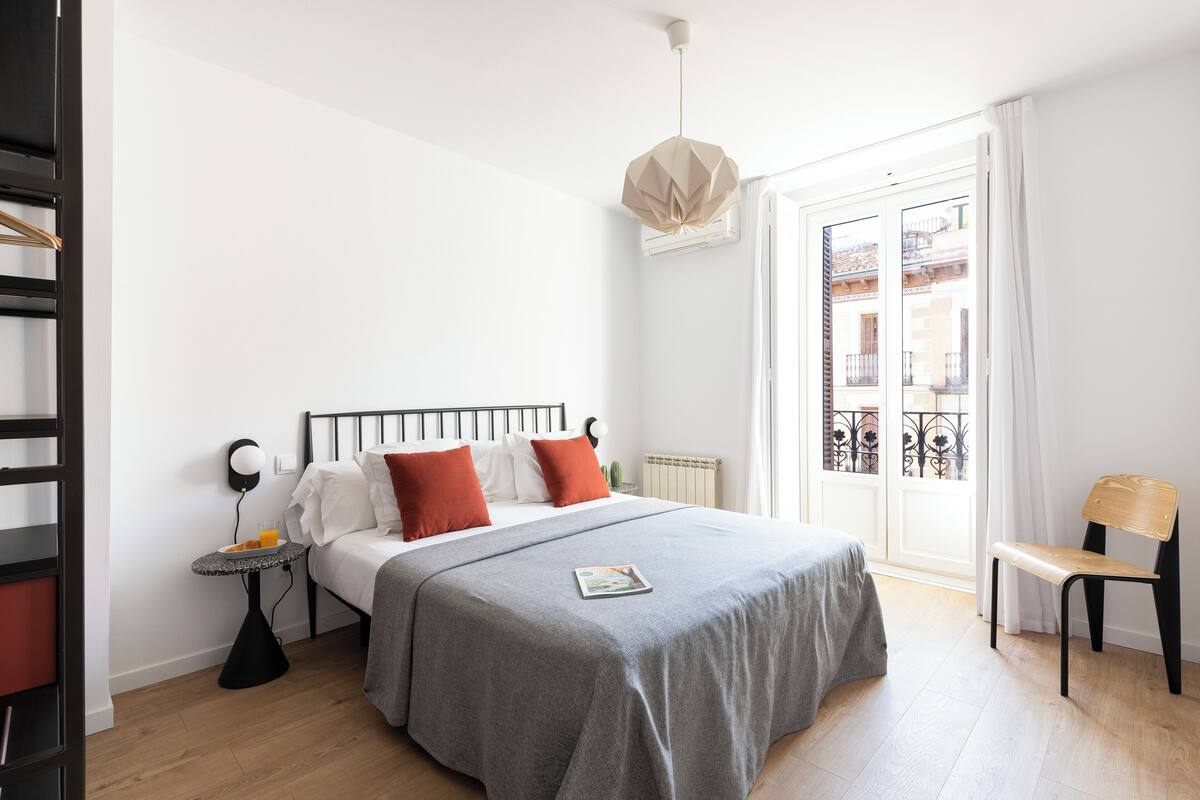 Een moderne slaapkamer met een bed, nachtkastje en stoel.