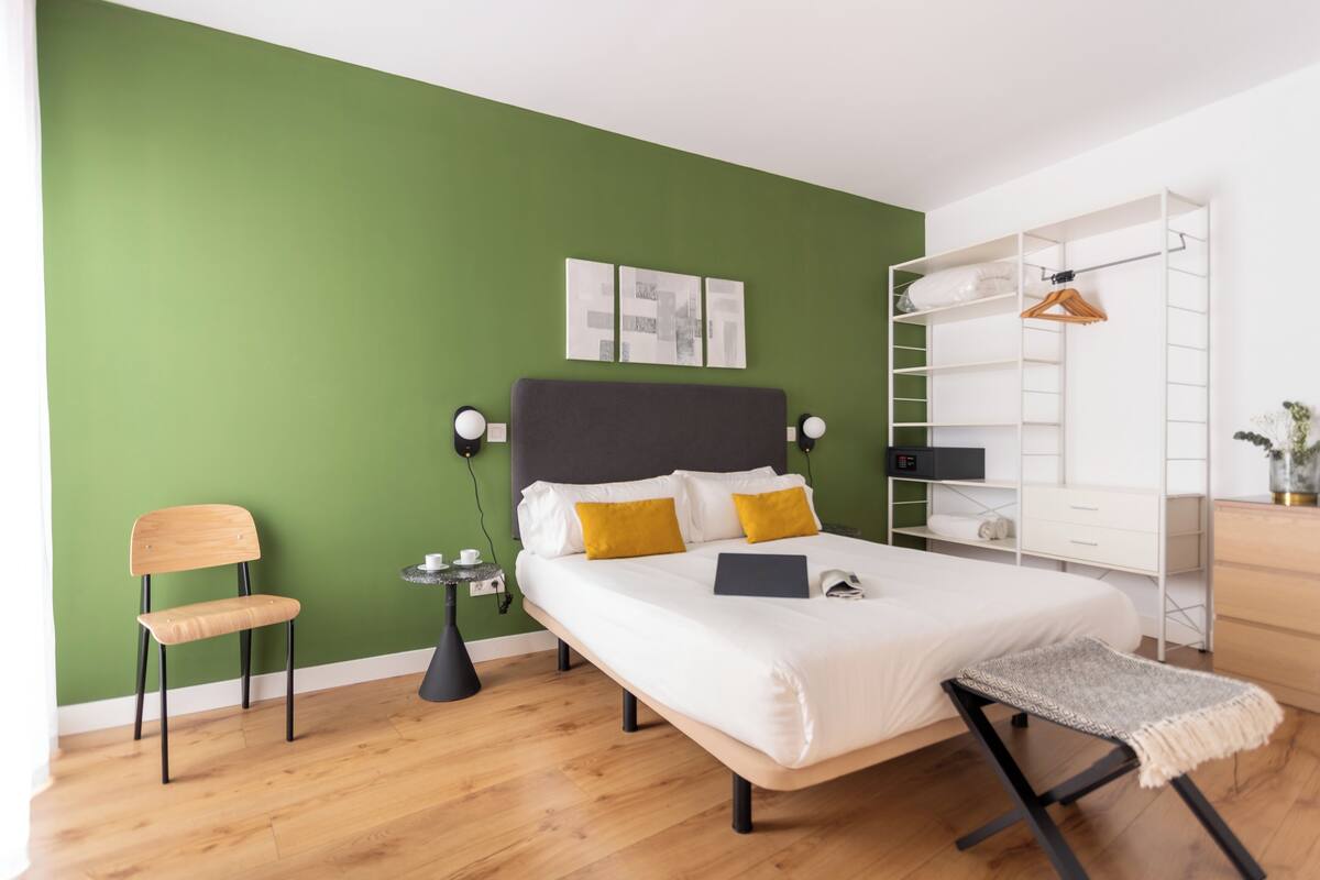 Een moderne slaapkamer met een bed, nachtkastje, stoel en een kledingkast.