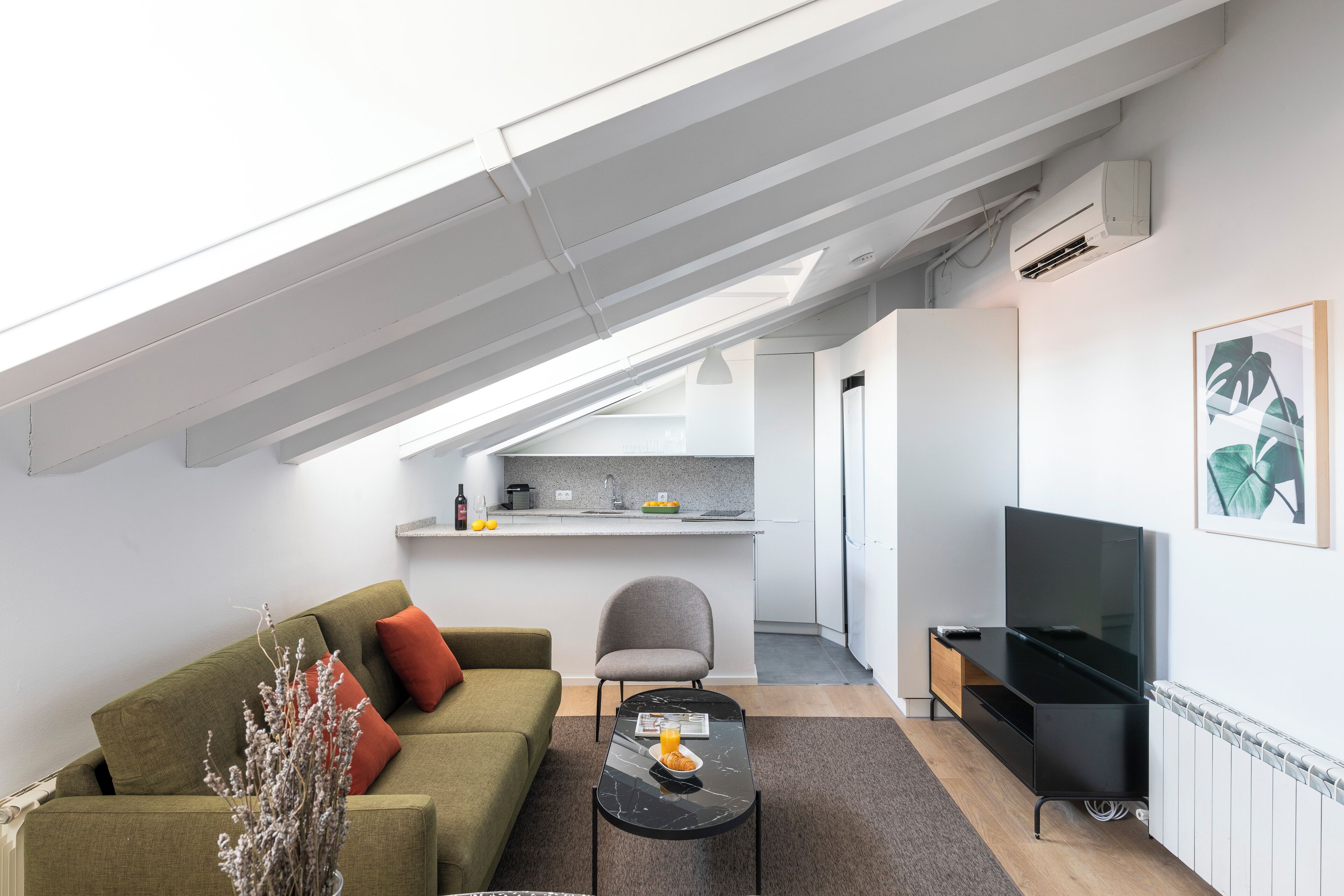 A modern apartment with a loft-style living area, a kitchen, and a dining space.