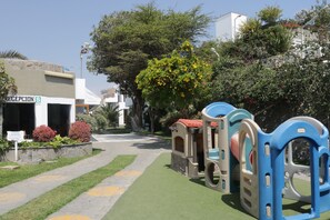A children's play area with a green turf path, a reception sign, and a building with a stone facade.
