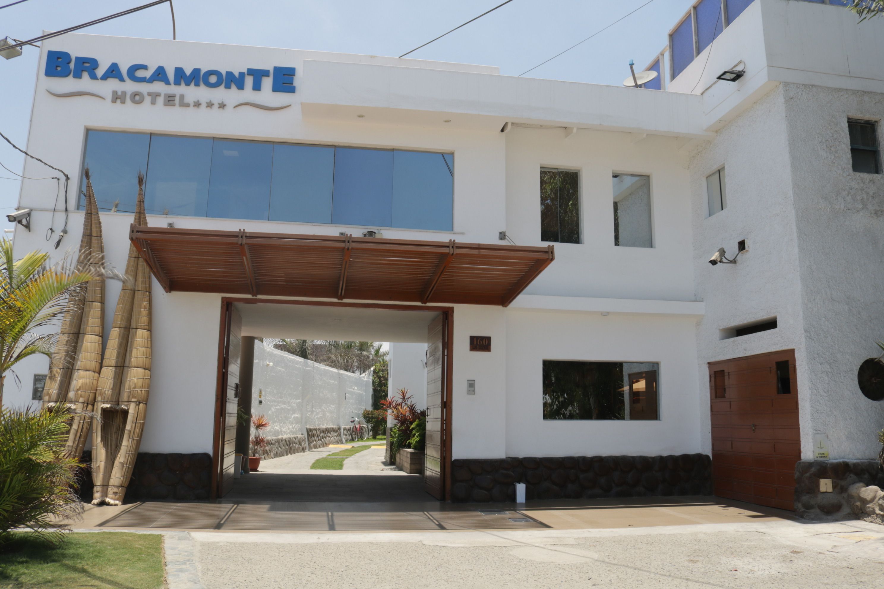 A hotel entrance with a covered walkway, a sign reading "BRACAMONTE HOTEL", and a view of the street beyond.