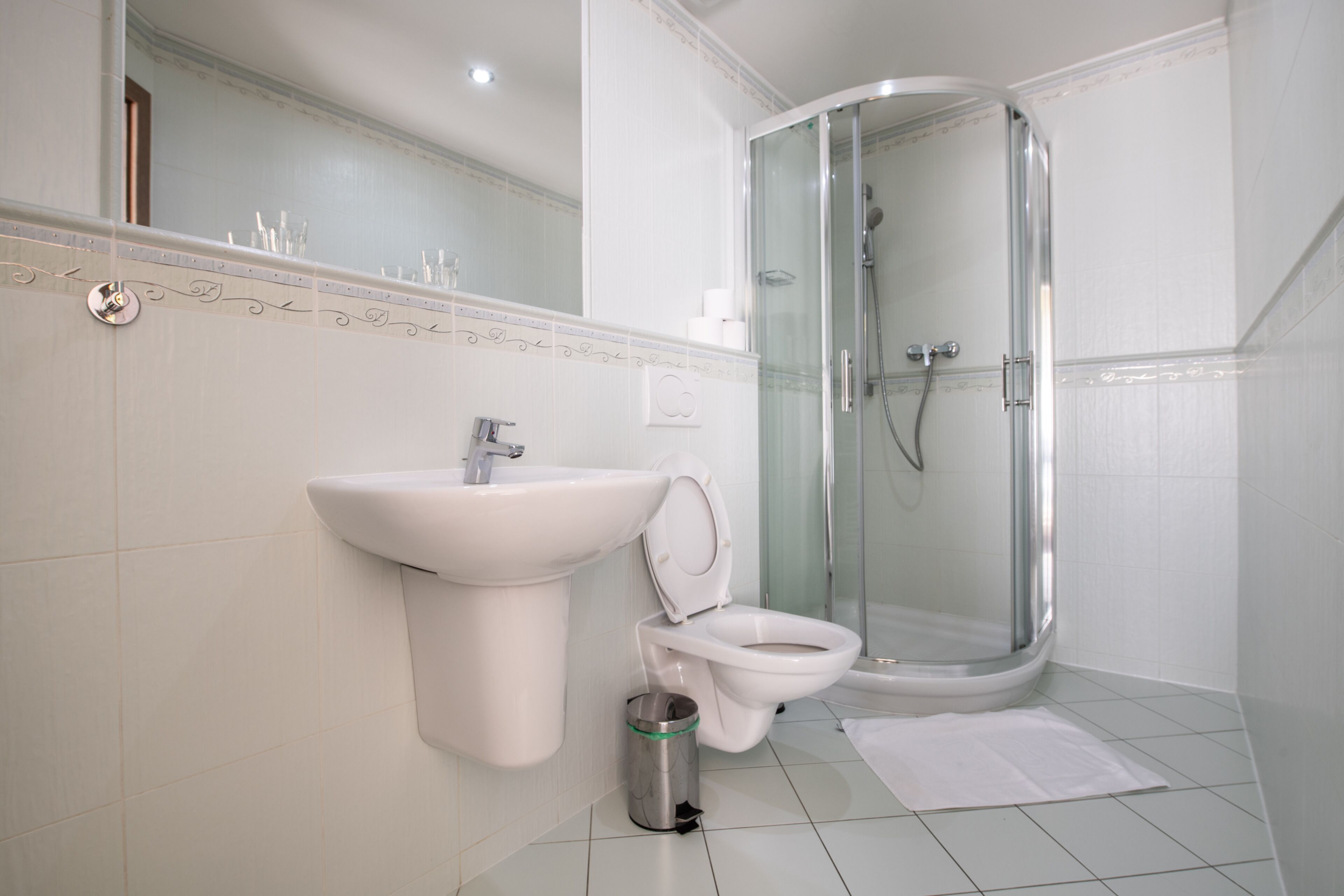 Une salle de bain moderne avec un lavabo blanc, des toilettes et une douche à parois de verre.