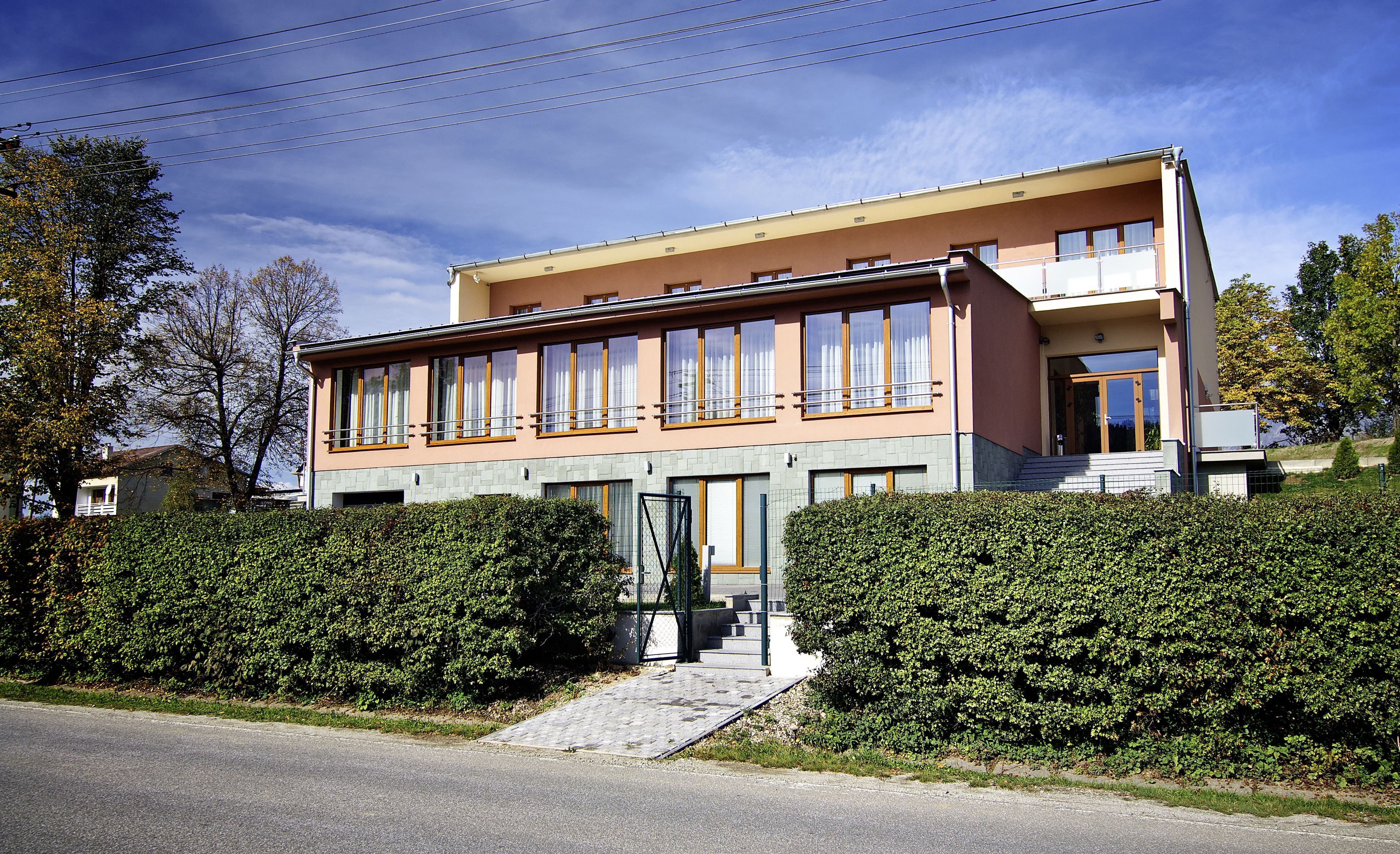 A modern two-story building with a flat roof, large windows, and a front entrance with steps.