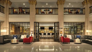 A spacious lobby with a high ceiling, a central bar area, and a seating area with red chairs. - Marriott Vacation Club® at the Mayflower, Washington, D.C. (Washington)