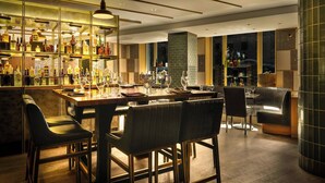 A bar area with a long counter, multiple stools, and a variety of bottles and glasses. - Marriott Vacation Club® at the Mayflower, Washington, D.C. (Washington)