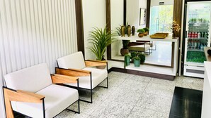 Un espacio moderno para relajarse con un sofá, sillas, una mesa de centro y un refrigerador lleno de bebidas.