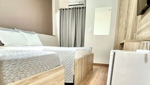 Una habitación de hotel con cama, escritorio y refrigerador.